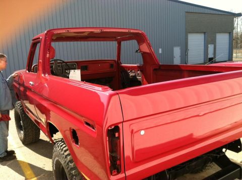 1978 Ford Bronco - A red 1978 Ford Bronco is shown from the rear three-quarter angle, with a person standing next to it. The vehicle appears to be undergoing…