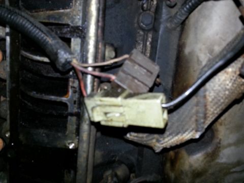 1994 Ford Bronco - Close-up view of a vehicle's engine wiring harness connector, showing wear and tear on the wires.