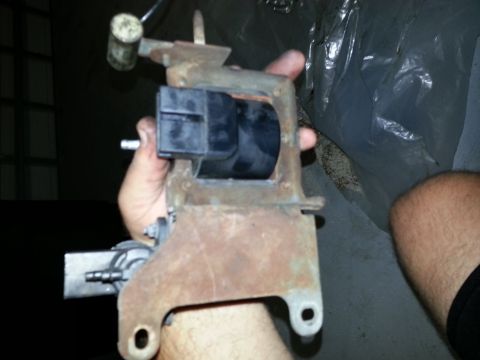 1994 Ford Bronco - A person holds a rusty automotive part with a black electrical connector.