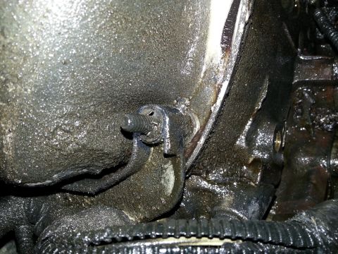 1994 Ford Bronco - Greasy engine part with a bolt and bracket visible.