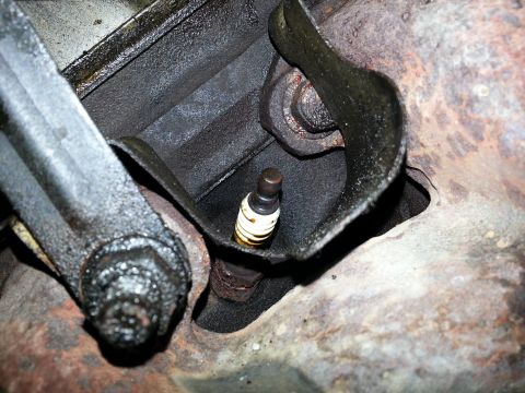 1994 Ford Bronco - Close-up view of a spark plug within the engine block, showing surrounding mechanical parts.