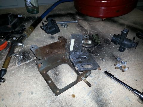 1994 Ford Bronco - Various vehicle parts and tools are spread across a workbench, suggesting a repair or maintenance project is underway.