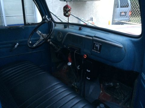 1968 Ford Mustang - The interior of a vintage blue truck features a custom steering wheel, a sticker on the dash, and a bench seat.