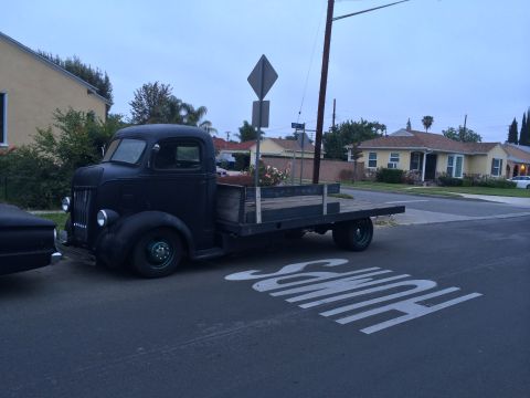 1968 Ford Mustang - An older model flatbed truck is parked on a residential street next to a speed bump.