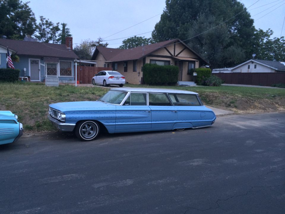 lowered blue station wagon parked on street, white roof, chrome wheels