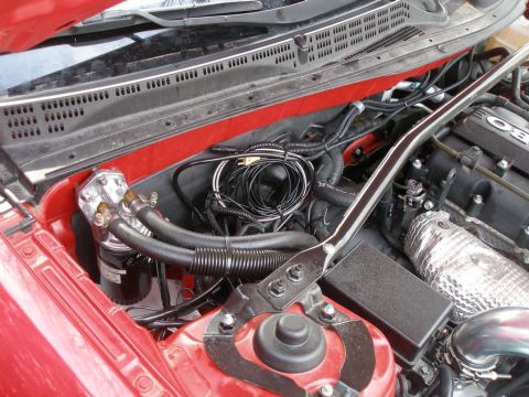 2010 Hyundai Genesis - Close-up of an engine bay shows an aftermarket oil cooler and various hoses and wiring.
