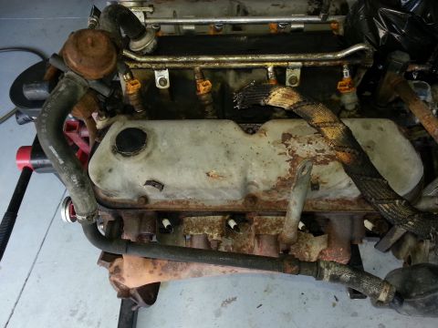 1994 Ford Bronco - Engine part with fuel injectors and spark plugs visible, showing signs of rust.