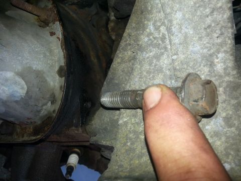 1994 Ford Bronco - Close-up view of a bolt being removed from a vehicle's engine assembly.