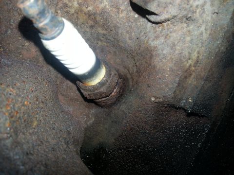 1994 Ford Bronco - Close-up of a spark plug installed in a corroded engine block.
