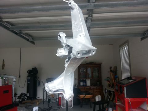 1994 Ford Bronco - A metal suspension component is suspended in a garage, awaiting installation or finishing.
