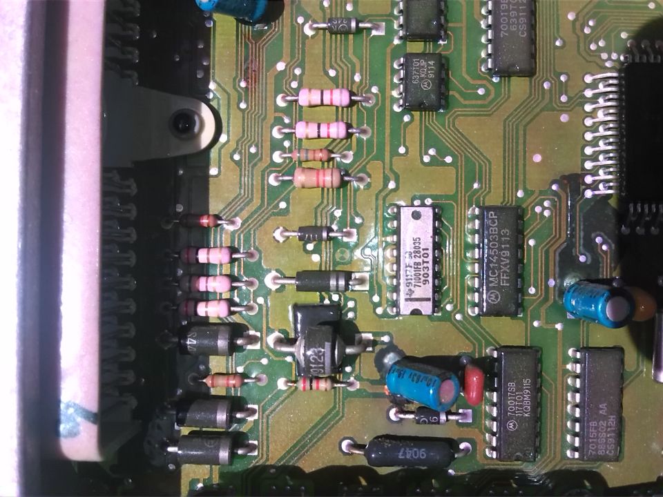 Close-up of a green circuit board with various electronic components including resistors, capacitors, and integrated circuits
