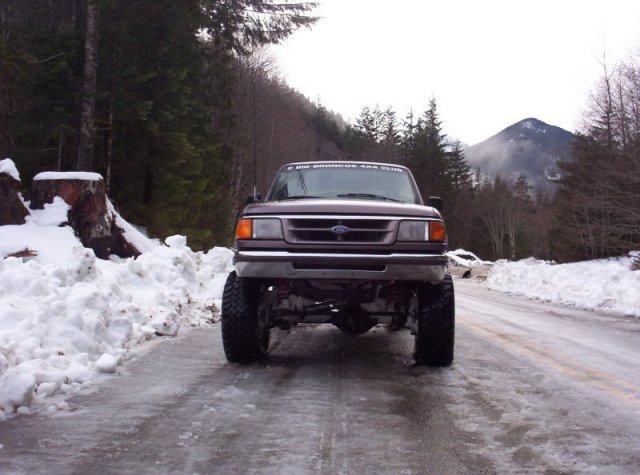 Brown Ford Ranger pickup truck with lifted suspension on a snowy, icy road