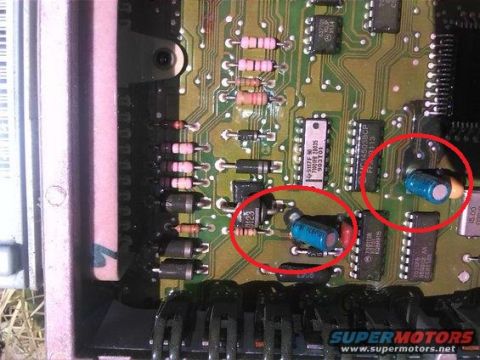 1994 Ford Bronco - Close-up of an electronic control unit's circuit board, highlighting two capacitors with red circles.