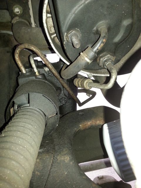 1992 Ford Bronco - Close-up view of a vehicle's power steering pump and associated hoses, showing mechanical components and fluid lines.