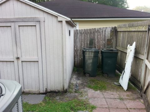 1992 Ford Bronco - A backyard scene shows a shed, trash cans, and a white panel leaning against a fence.