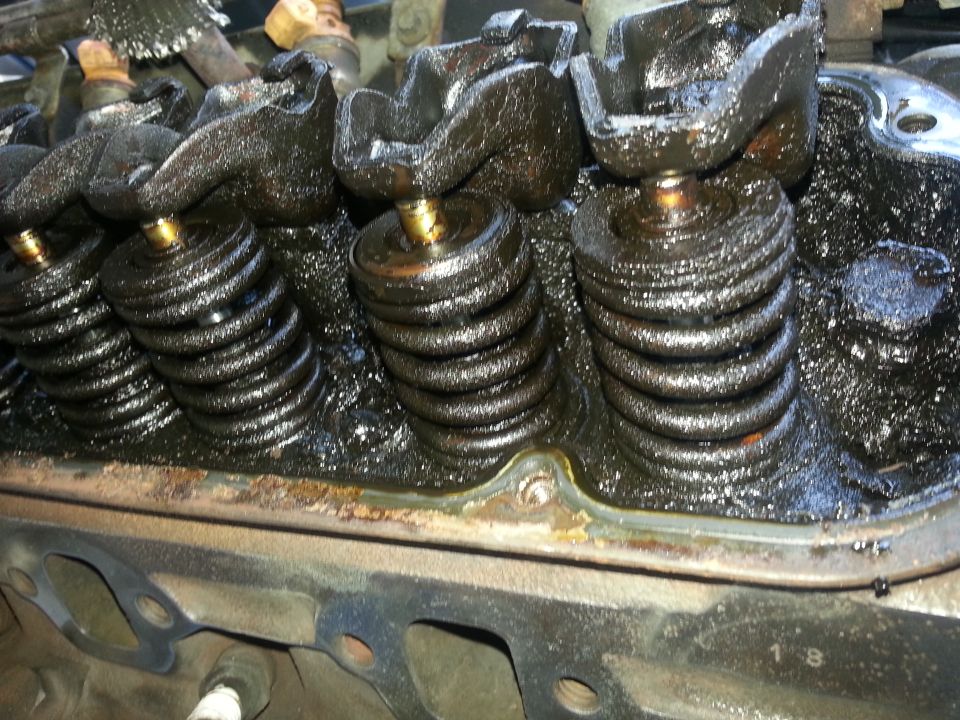 Engine valve train with black sludge covering springs and rockers