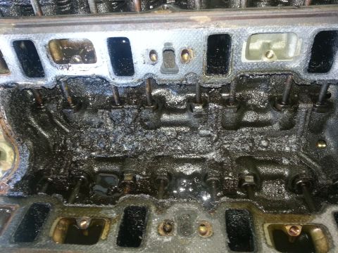 1994 Ford Bronco - Close-up of a heavily sludged engine cylinder head, obscuring internal components.