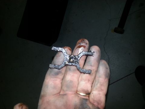 1994 Ford Bronco - A greasy metal part is held in a dirty hand, possibly from a vehicle repair.