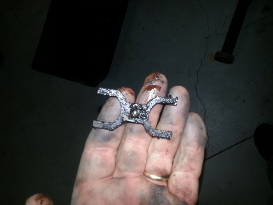Metal part held in a dirty hand with a ring
