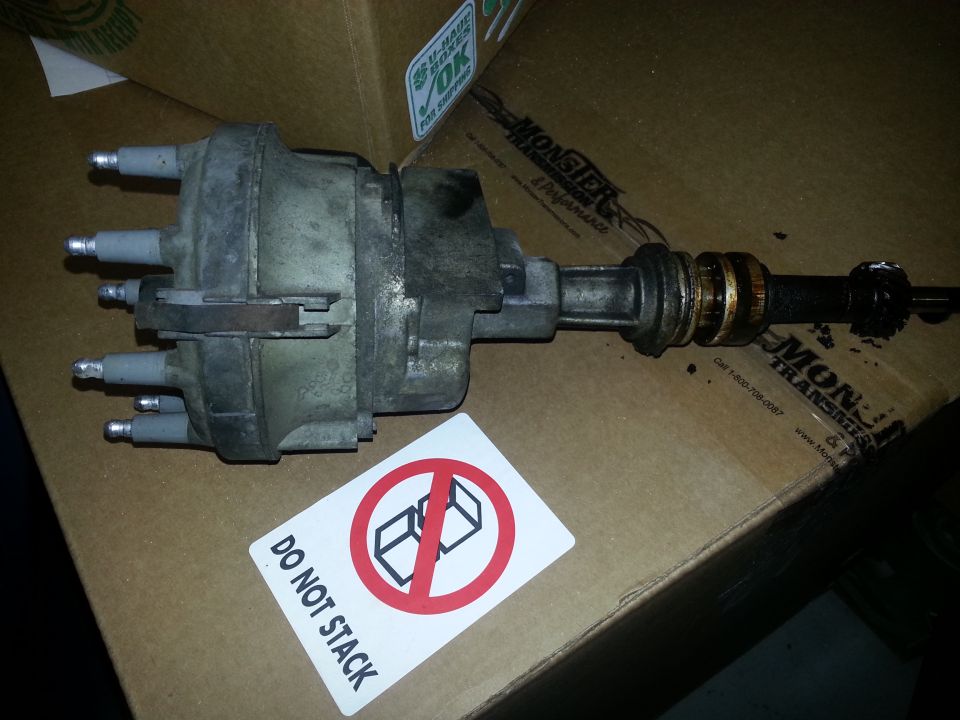 Distributor with wires and shaft, sitting on a cardboard box with a 'Do Not Stack' sticker