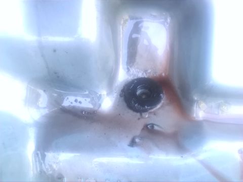 1992 Ford Bronco - The oil pan drain plug is visible with some fluid staining around it.