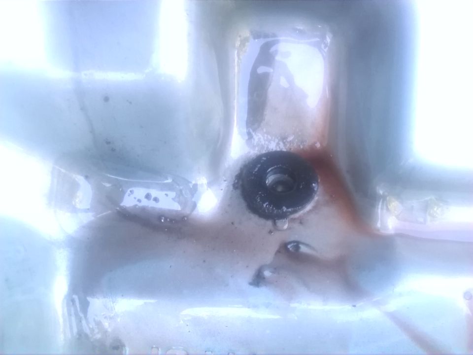 oil pan drain plug with some reddish fluid around it