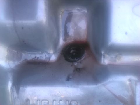 1992 Ford Bronco - Close-up of a vehicle's transmission pan, revealing a drain plug and fluid leakage.