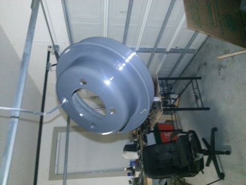 1994 Ford Bronco - A freshly painted brake rotor is suspended in a workshop environment.
