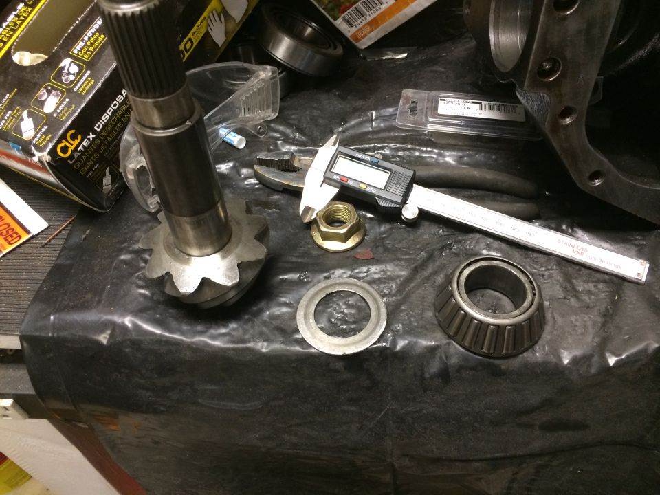 Differential ring gear, bearing, nut, and digital caliper on black surface