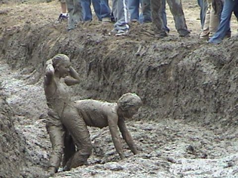 1982 Ford Bronco - People covered in mud struggle in a trench during an event.