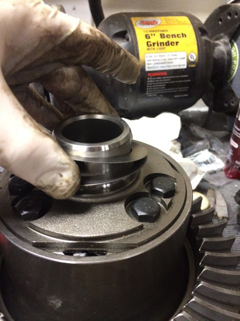 1996 Ford Bronco - Gloved hand seating a bearing onto a differential carrier on a workbench beside a Sears 6-inch bench grinder.