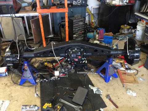 1996 Ford Bronco - A rear axle assembly is shown on jack stands in a workshop environment, surrounded by tools and equipment.