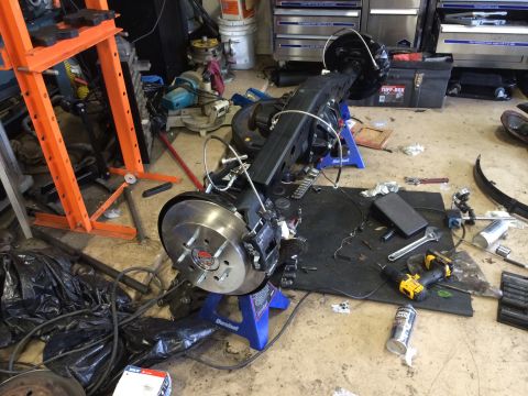 1996 Ford Bronco - Rear axle assembly, likely from a 1996 Ford Bronco, is disassembled and supported by jack stands in a workshop.
