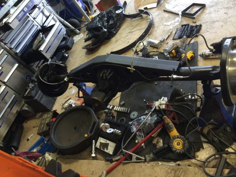 1996 Ford Bronco - A disassembled rear axle assembly sits amidst a collection of tools and automotive parts in a workshop setting.