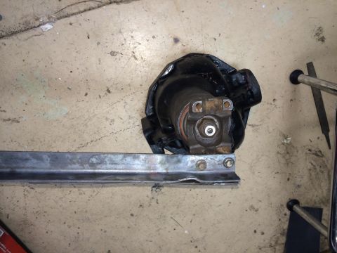 1996 Ford Bronco - A close-up view of a vehicle differential component and a metal bracket on a workshop floor.