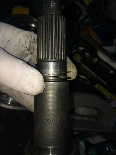 1996 Ford Bronco - A gloved hand holds a splined shaft, showing a retaining ring and some stamped markings.