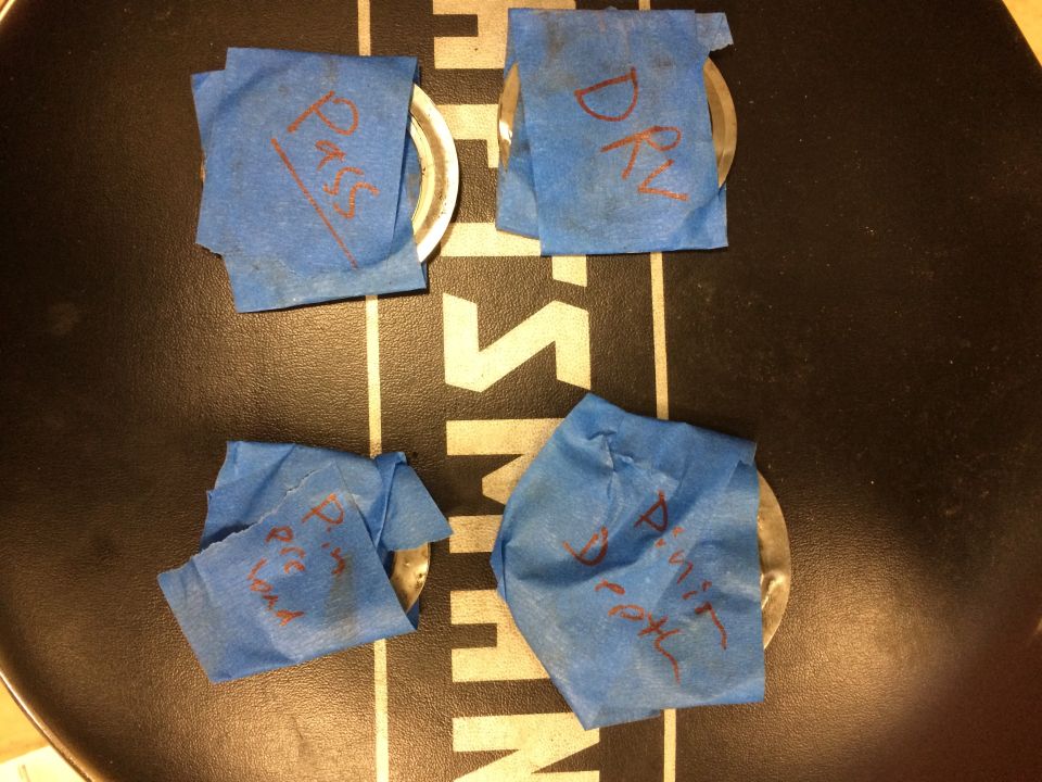 four metal parts wrapped in blue tape, each with red writing on it