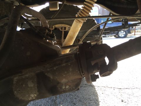 1996 Ford Bronco - Close-up view of the rear axle and suspension system of a vehicle, with another truck in the background.