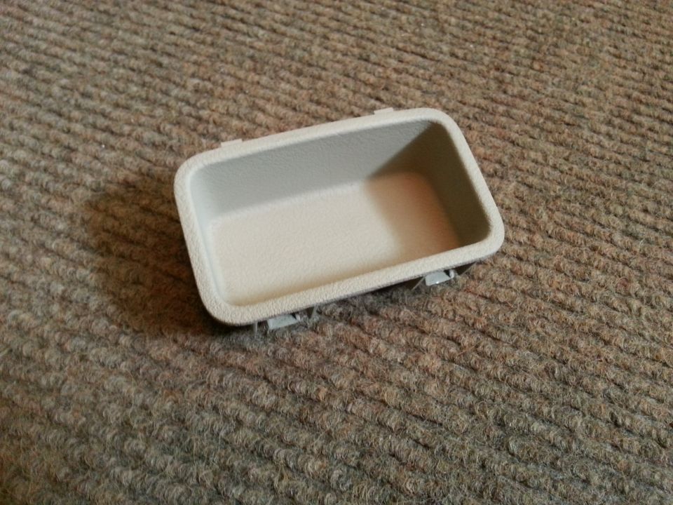 tan plastic interior trim piece with clips on the bottom, on carpet