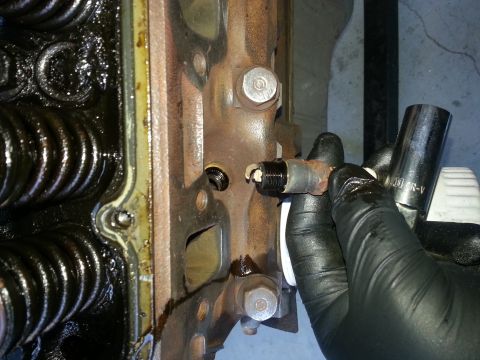 1994 Ford Bronco - Removing a spark plug from an engine block with a socket wrench.