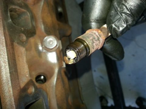 1994 Ford Bronco - A person is removing a fouled spark plug from an engine block.