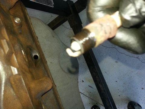 1994 Ford Bronco - A gloved hand holds a used spark plug near a corroded engine part.