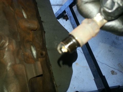 1994 Ford Bronco - Spark plug removed from engine block, showing signs of wear and fouling.