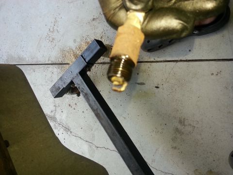 1994 Ford Bronco - A spark plug is shown being held by a gloved hand, resting on a metal tool on a concrete surface.