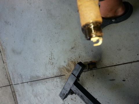 1994 Ford Bronco - A fouled spark plug is held over a concrete floor, indicating potential engine issues.