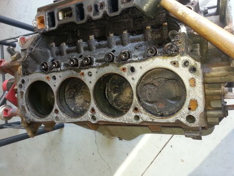 1994 Ford Bronco - Engine block with pistons visible, showing signs of wear and damage. A hammer is present.