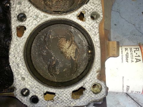 1994 Ford Bronco - This image shows a close-up view of a damaged engine cylinder and piston, with an oil filter attached to the side.