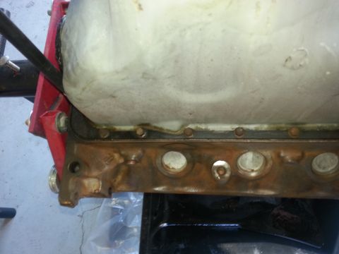 1994 Ford Bronco - Close-up view of an engine oil pan, showing the gasket and mounting bolts. The part is secured to a red engine stand.