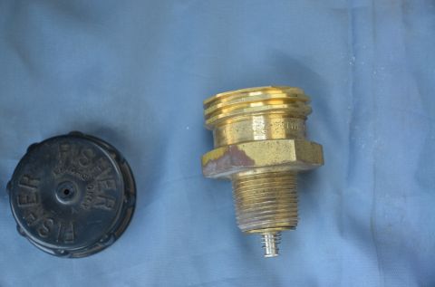 1979 Ford Bronco - A brass fitting and a black cap are shown against a blue cloth background.