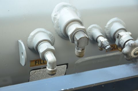 1979 Ford Bronco - Close-up view of multiple valves and fittings on a propane tank, including a label indicating 'FILL'.